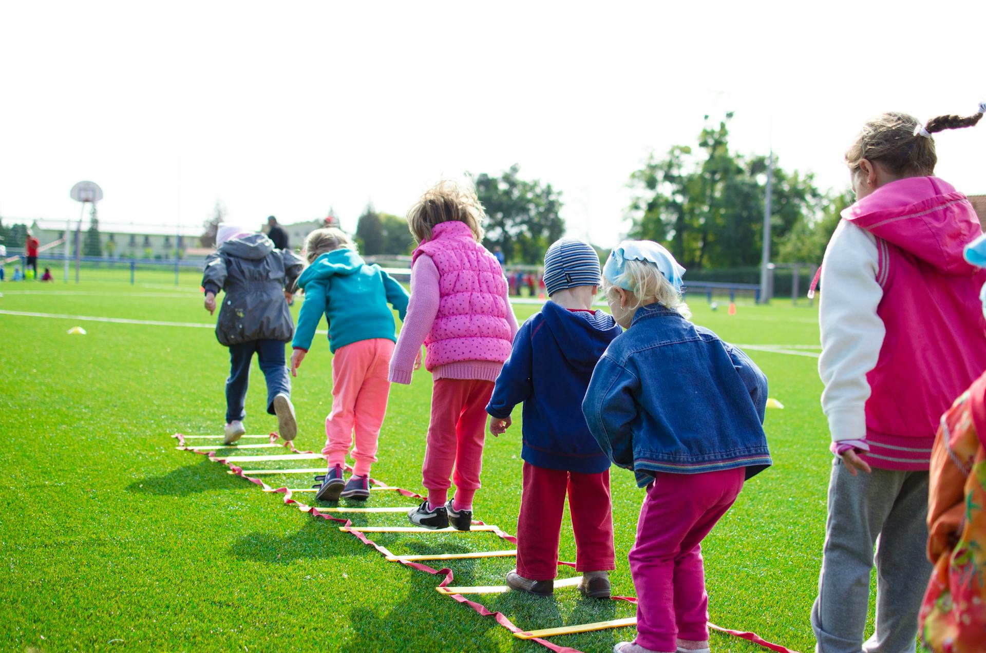 Young kids play in a line outdoors.