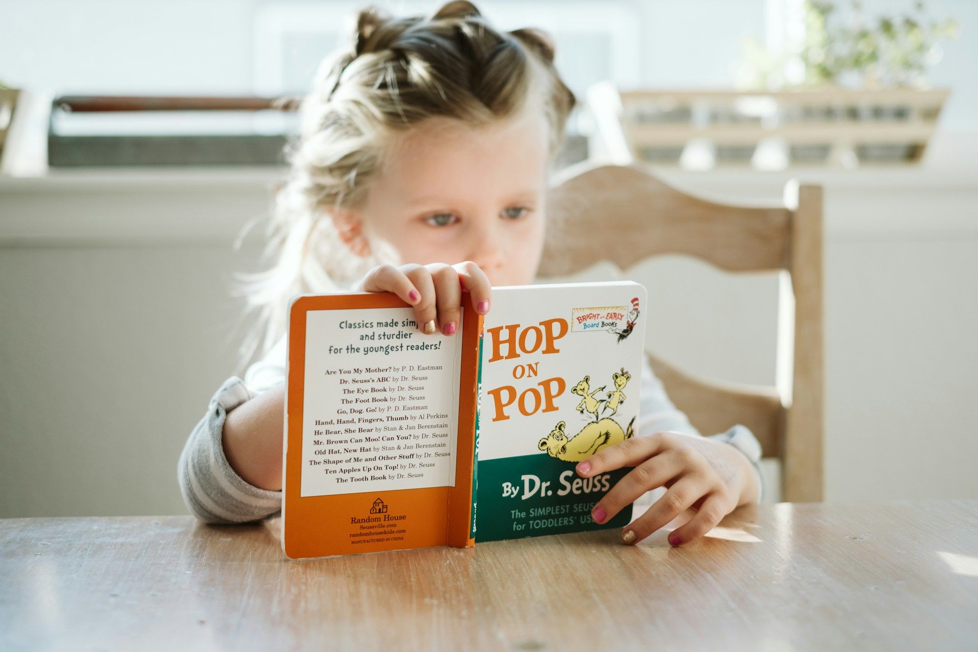 Young child reads a book by Dr Seus.