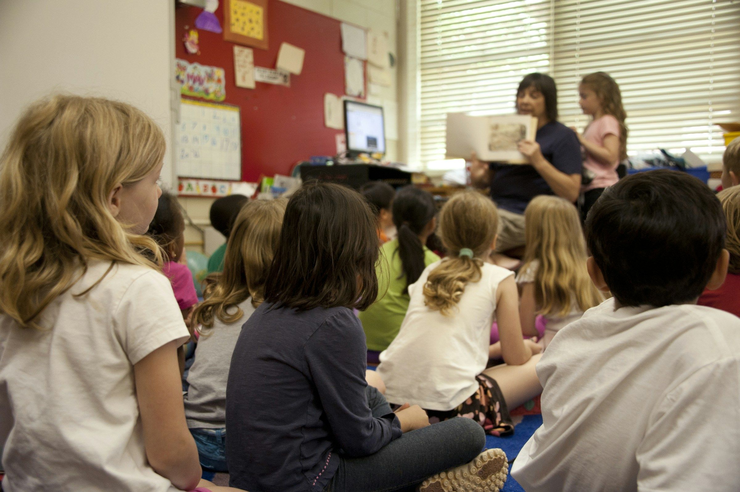 Young kids sat on the floor in a classroom for reading time.