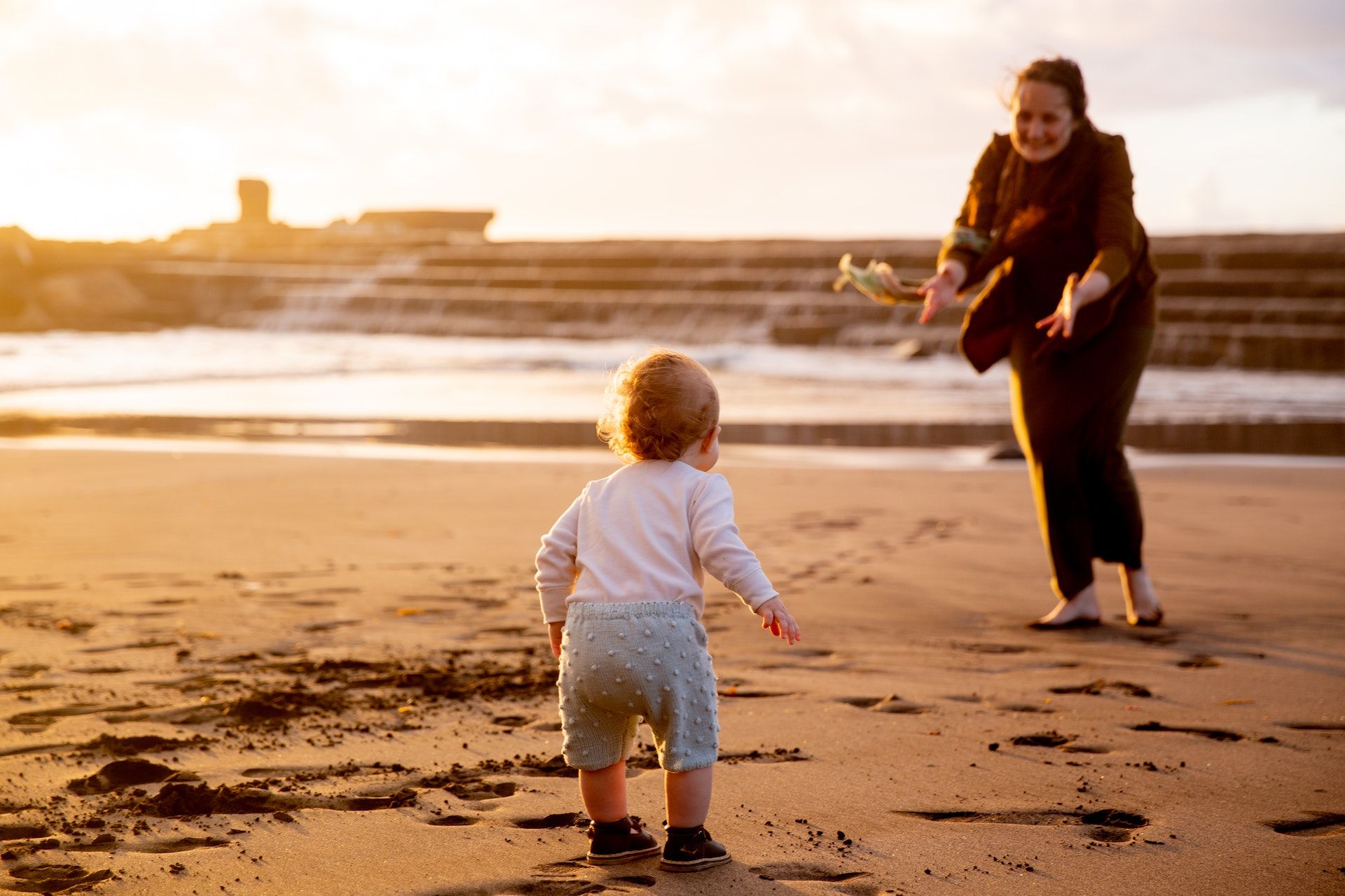 Baby running to mum on beach.