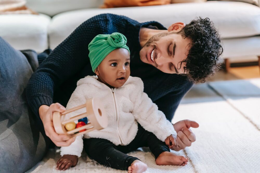 Baby with toy and parent.