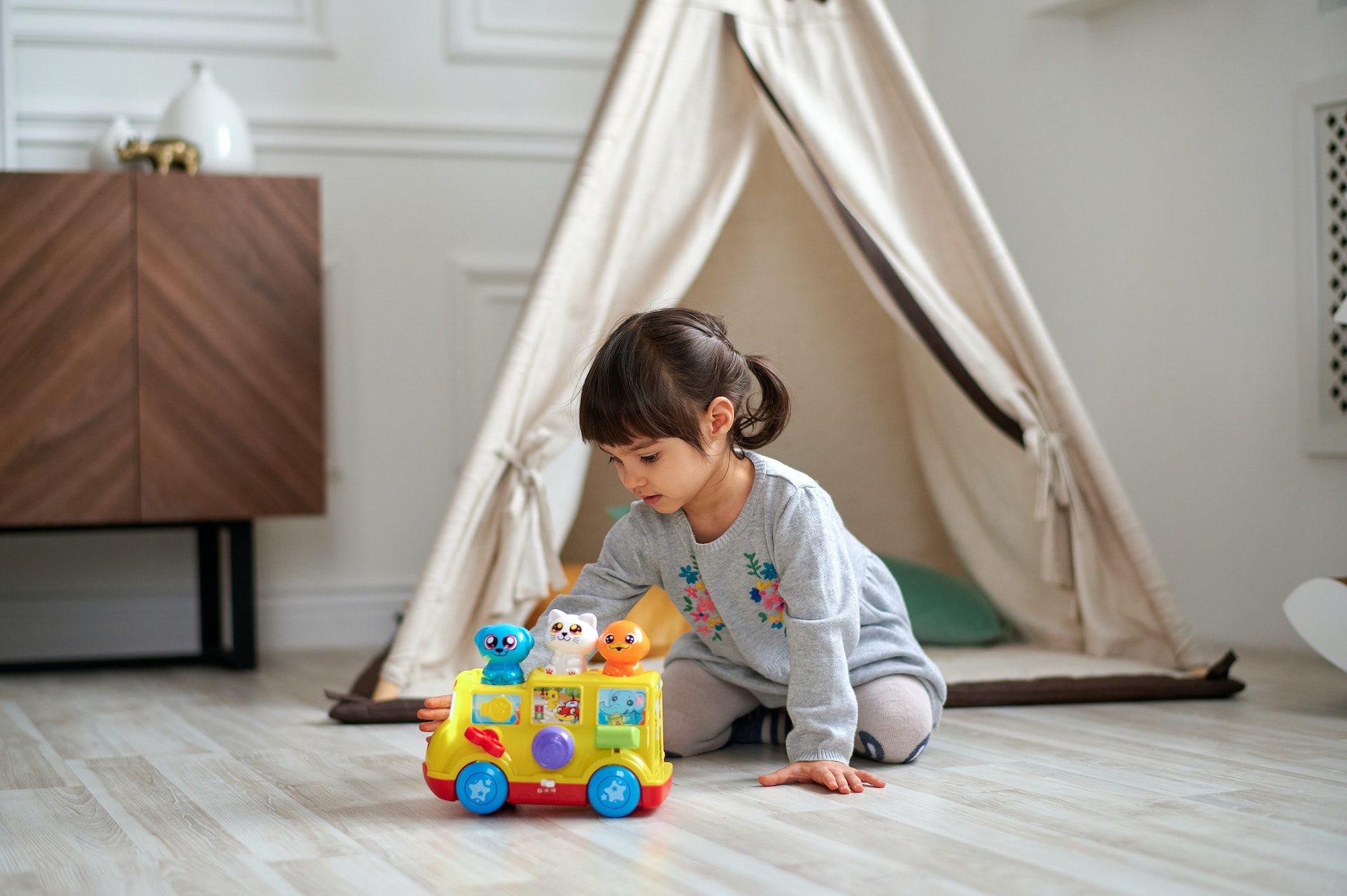 Child plays with toy by tent.