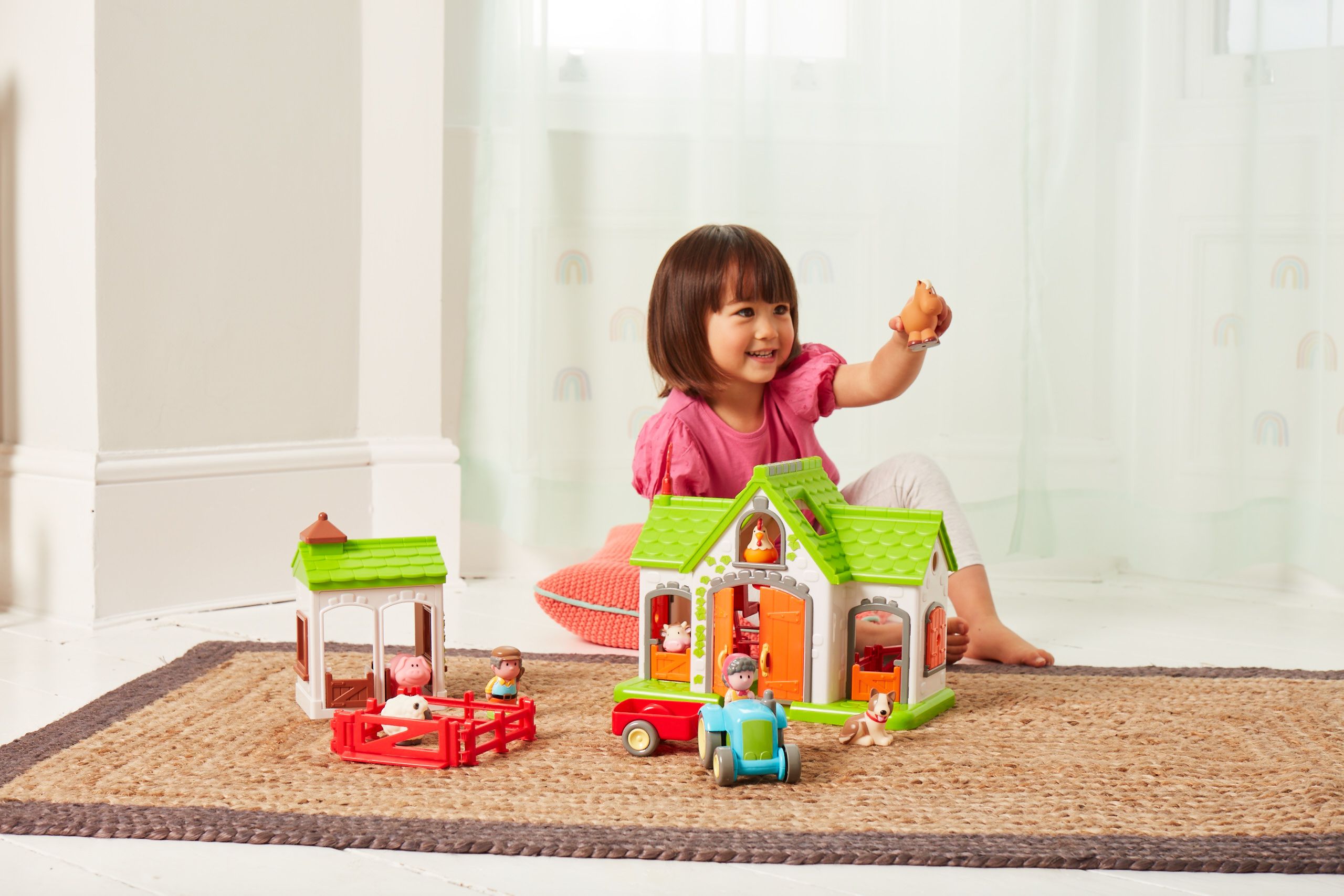 Happyland Farm Playset, a girl holds up a toy and enjoys playing with the set.