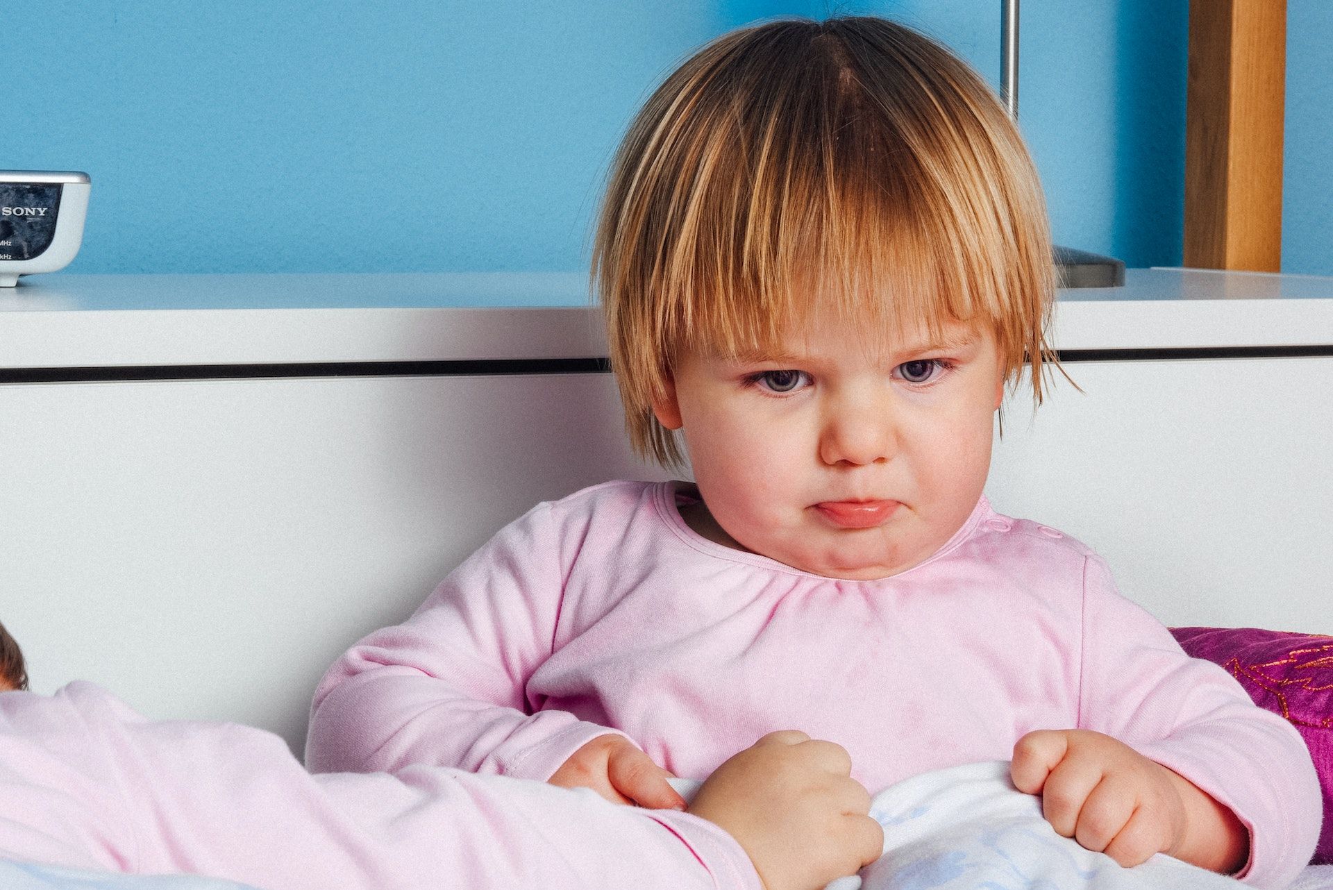 A moody little girl is having a mood swing and has a frown on her face.