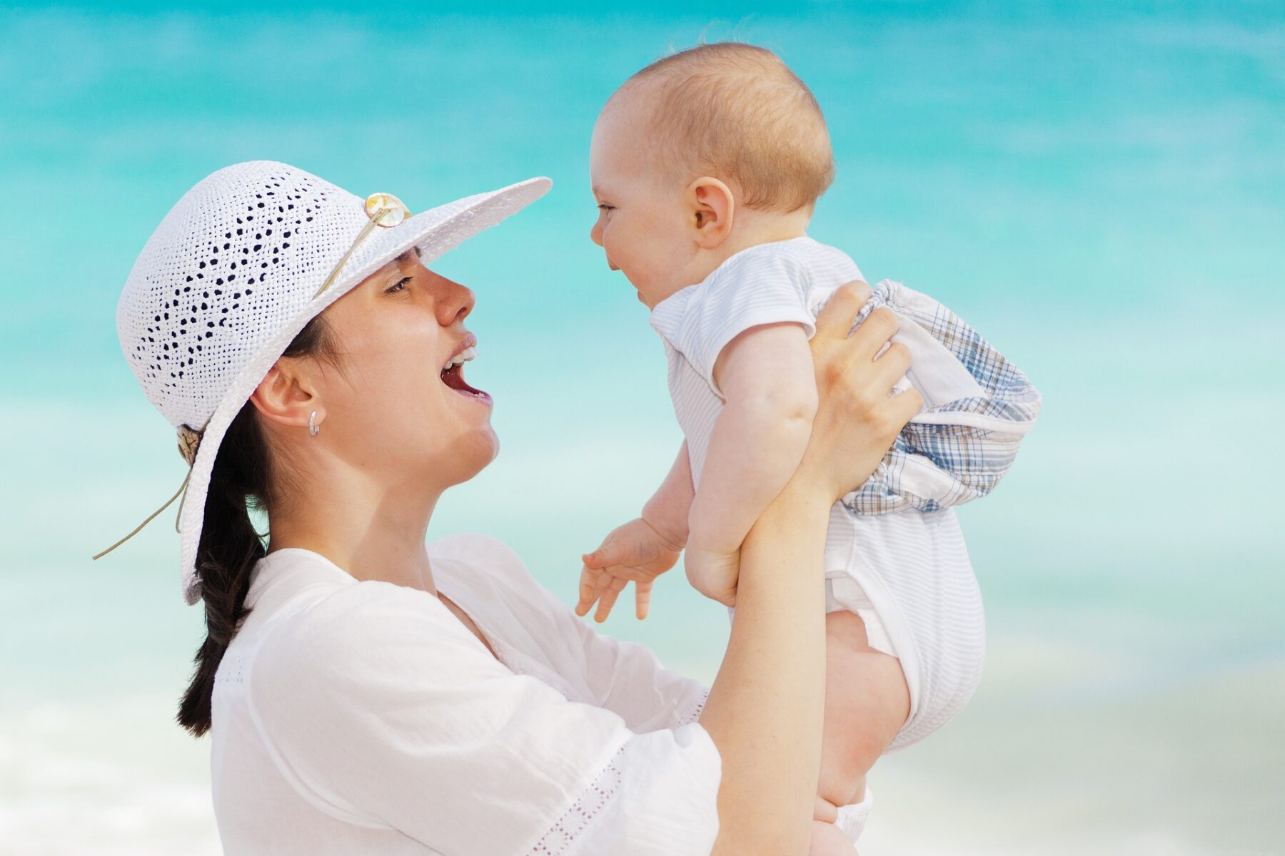 Mother holds baby up on holiday.