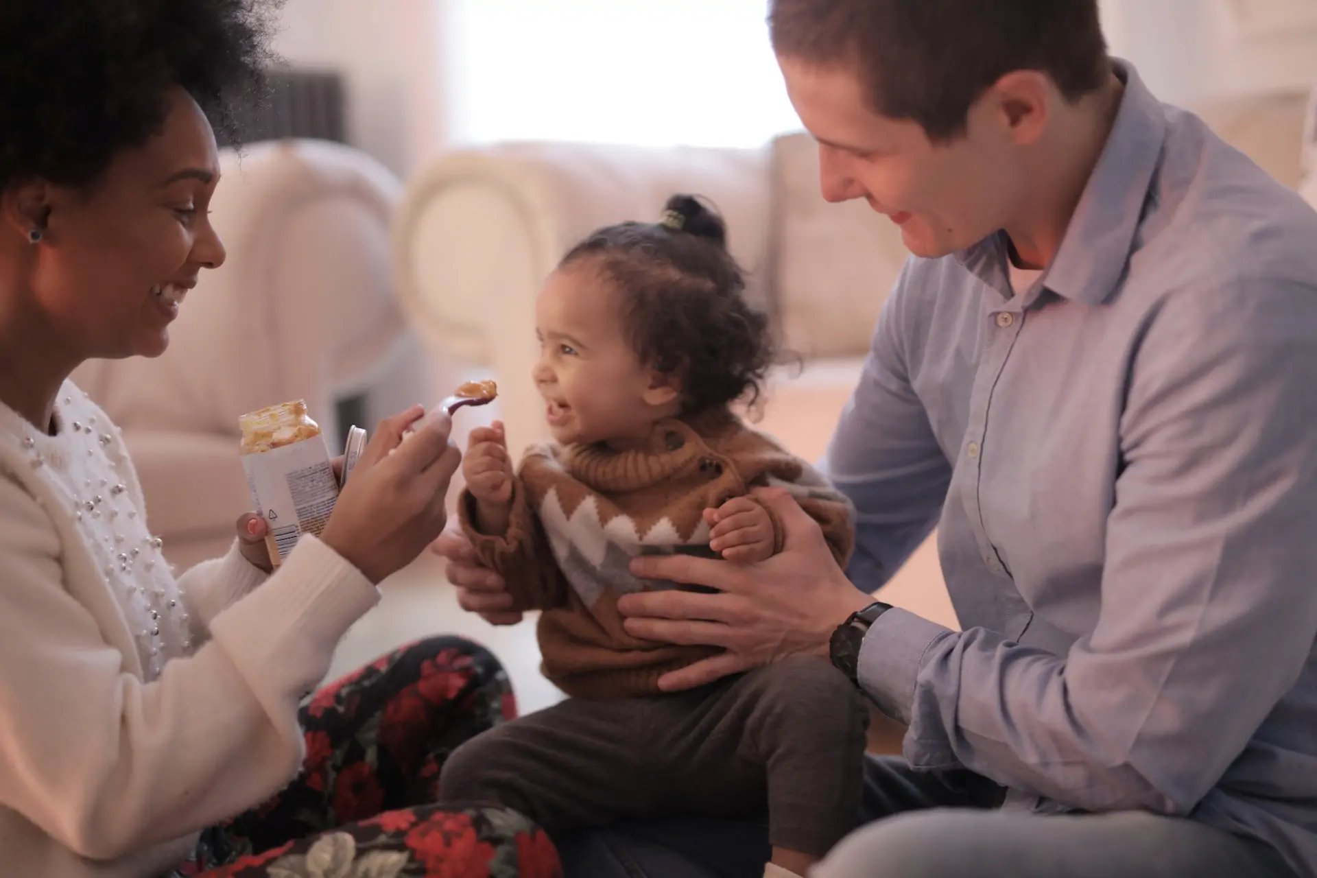 Parents feed their baby as they all laugh