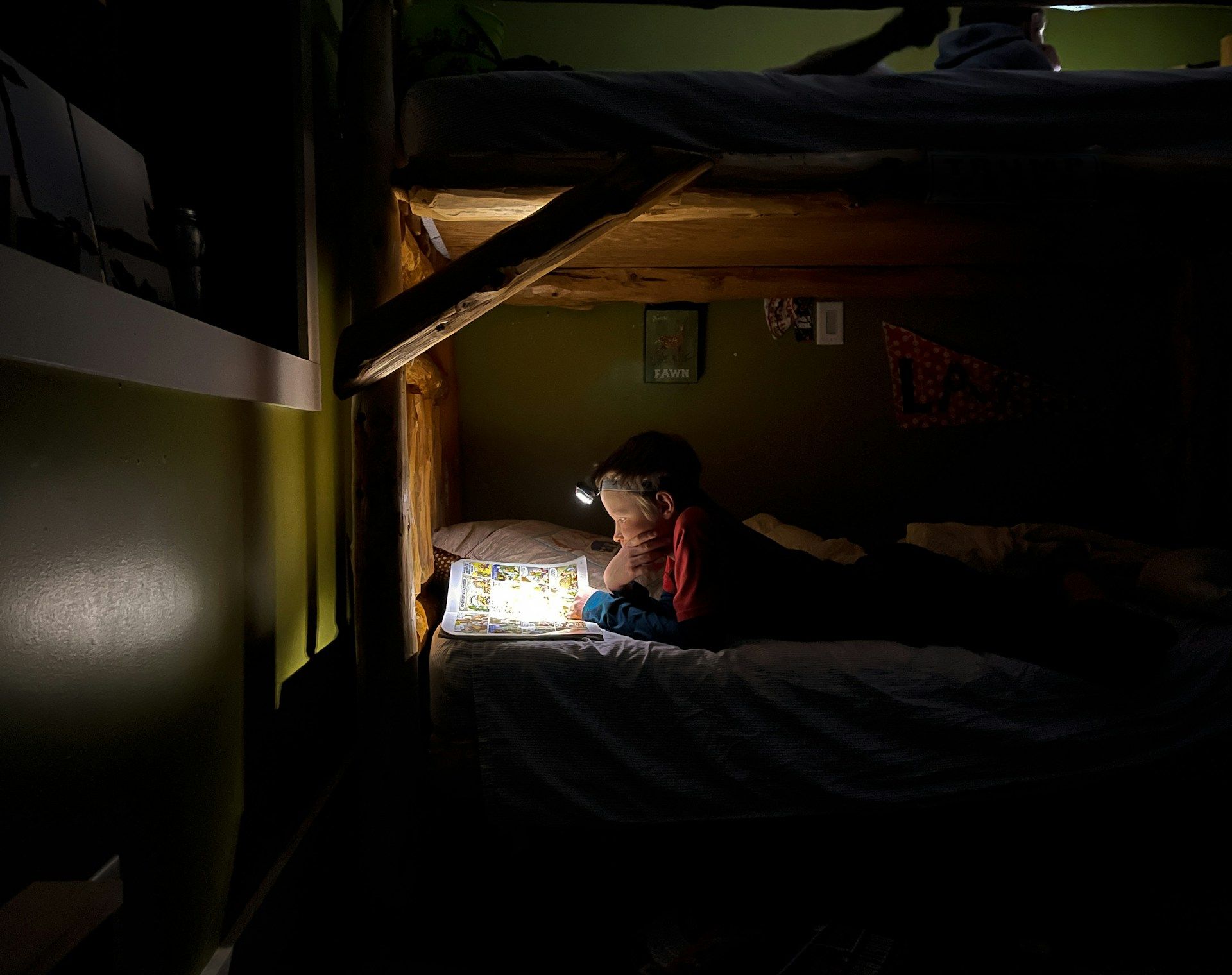 Child gets ready for bed by reading a book while laying down.