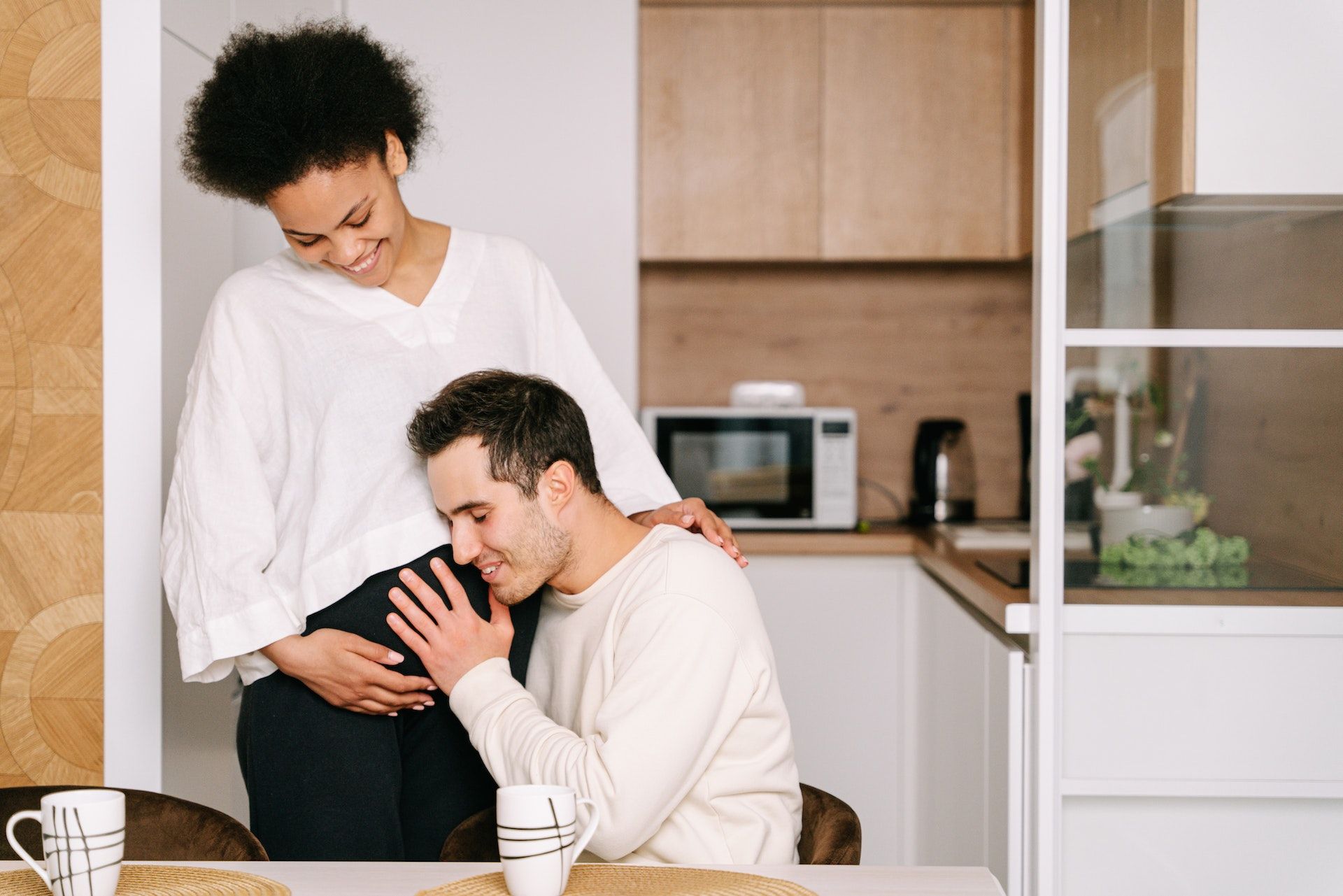 A pregnant woman has her belly rubbed by her partner.