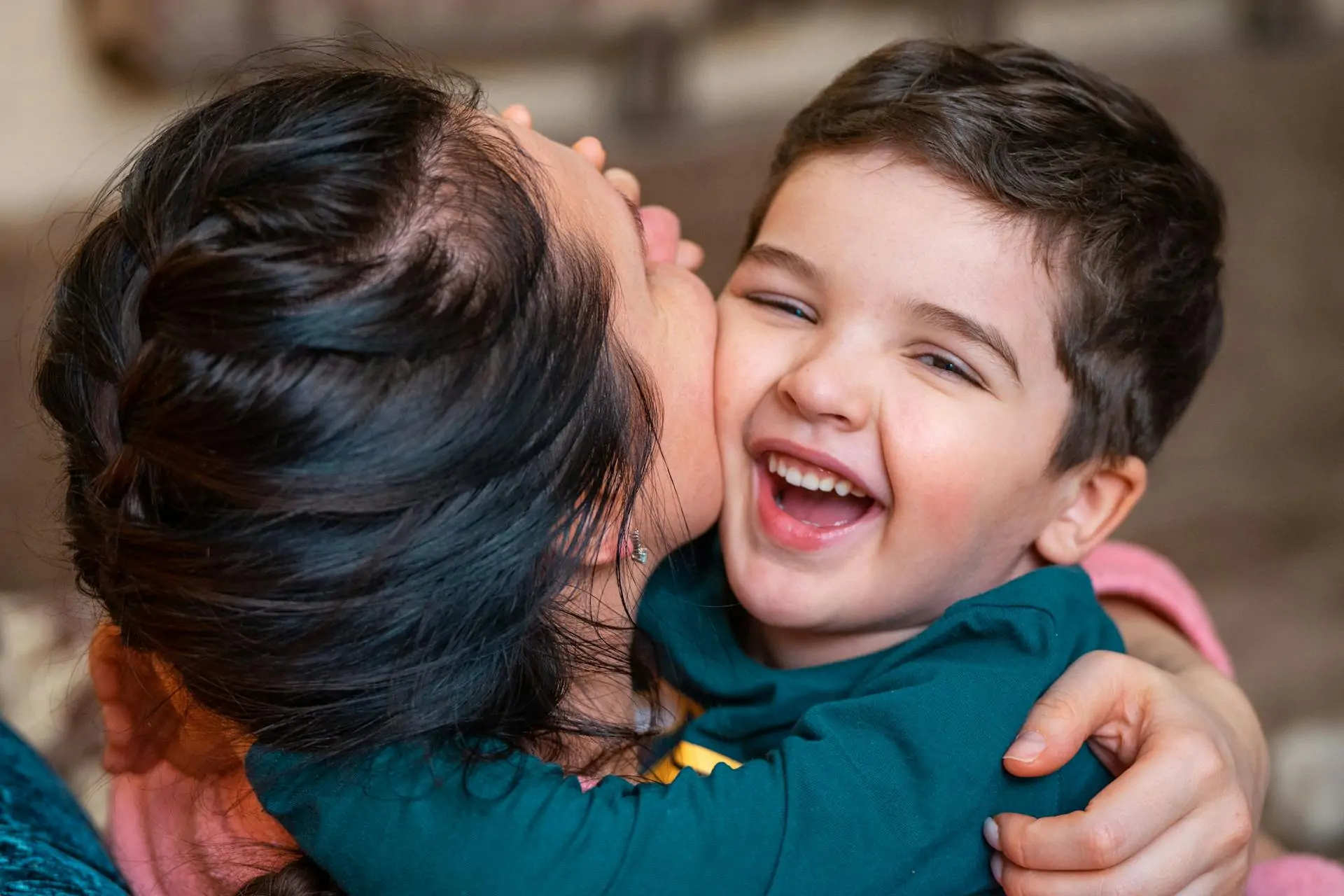 Child hugs an adult tightly while laughing.