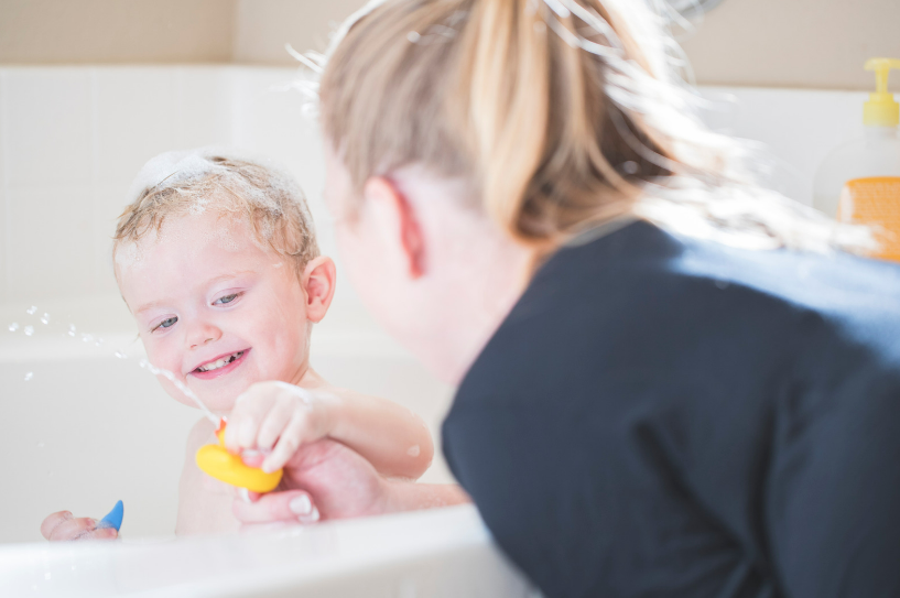 Baby in bath with bath toys.