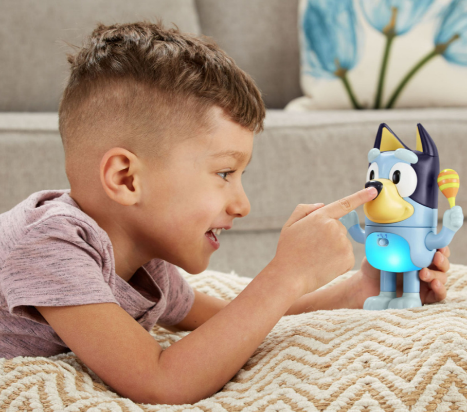 Toddler plays with interactive Bluey toy.