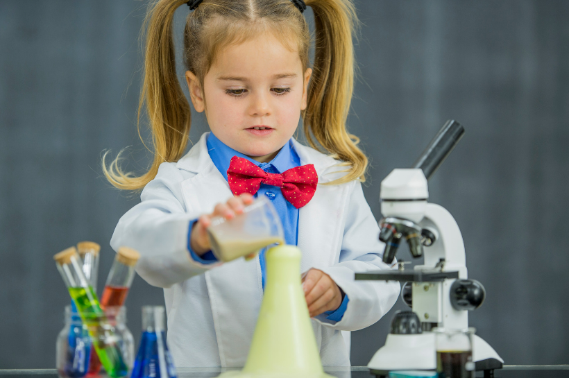 Child in a lab coat doing an experiment.